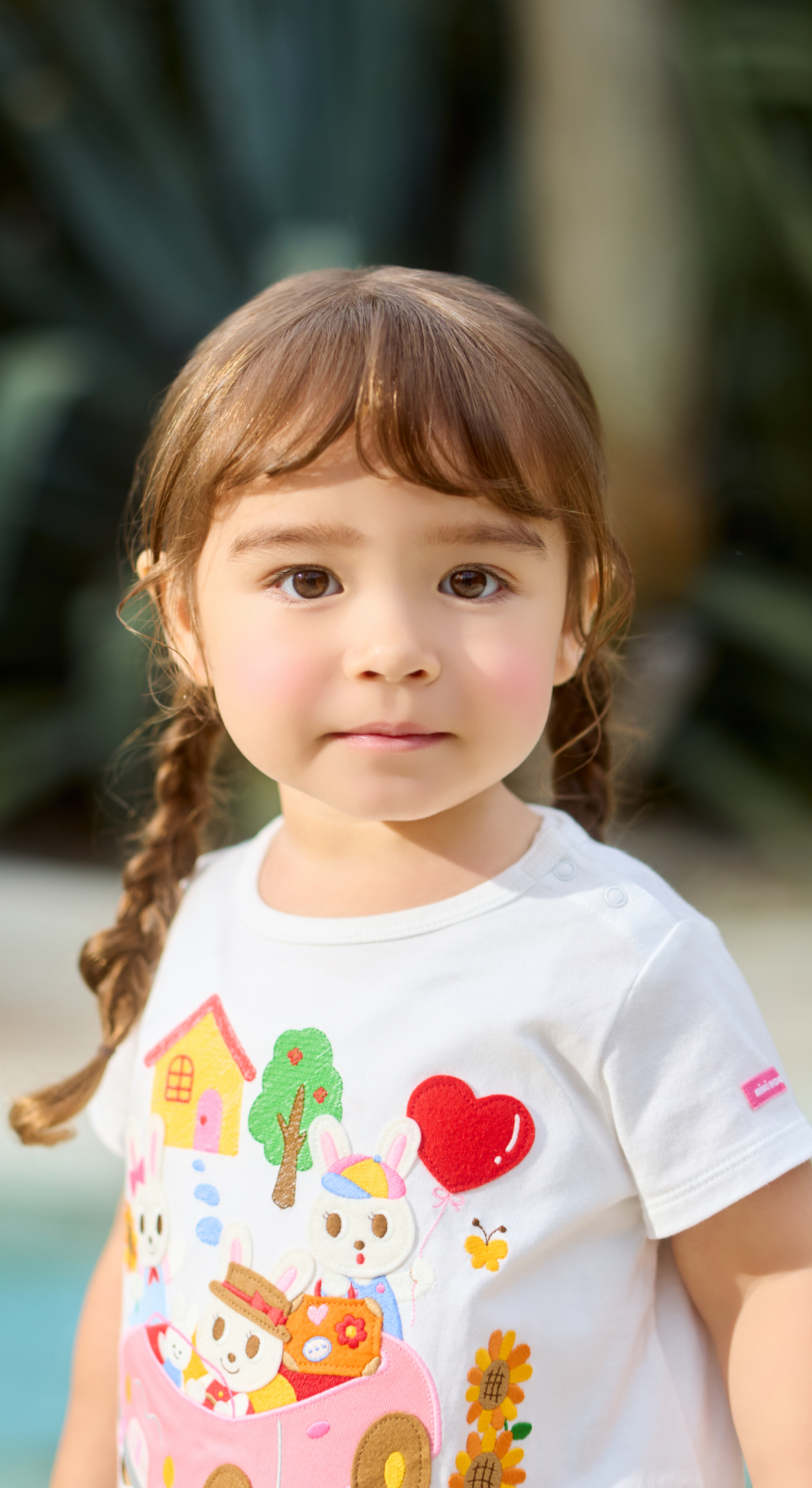 「DOUBLE.B」と描かれたカラフルな帽子とトレーナーを着た子どもが、上を見上げる姿